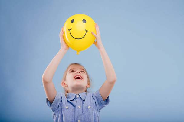 happy kid girl holds up yellow balloon with smile.  - Foto, Bild