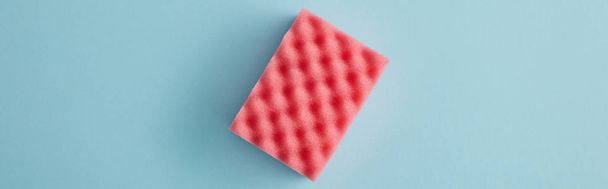 panoramisch shot van roze spons voor huisreiniging op blauw - Foto, afbeelding