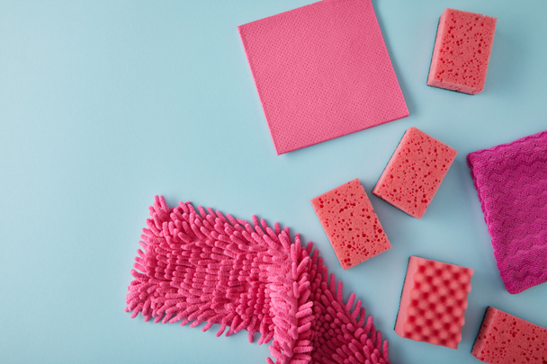 top view of pink rags and sponges for house cleaning on blue - Foto, Imagen