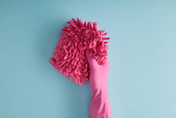 вид зверху домогосподарки в гумовій рукавичці, що тримає рожеву ганчірку на синьому
  - Фото, зображення