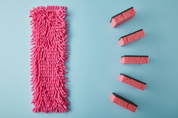 flat lay with pink rag and sponges for house cleaning on blue - 写真・画像