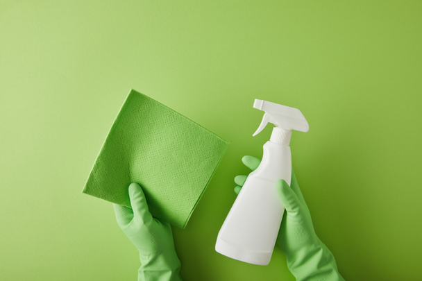 top view of housekeeper in rubber gloves holding rag and spray bottle on green  - Photo, Image