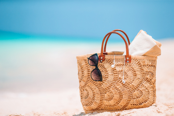 Strand kiegészítők - szalma táska, kalap és napszemüveg a strandon - Fotó, kép