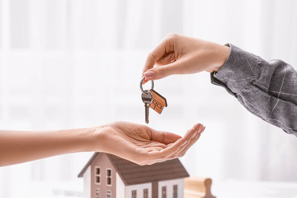 Агент по недвижимости дает ключ от нового дома клиенту в офисе
 - Фото, изображение