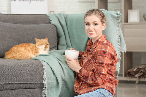 Gyönyörű fiatal nő aranyos macska ivás tea otthon - Fotó, kép