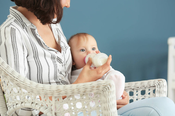 Äiti ruokkii vauvaa maidolla pullosta kotona
 - Valokuva, kuva
