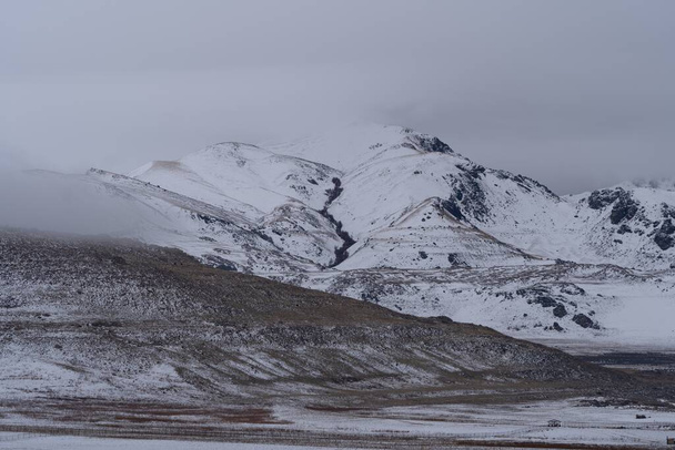 Beautiful scenery of snowy mountains on a dark gloomy day - Fotó, kép