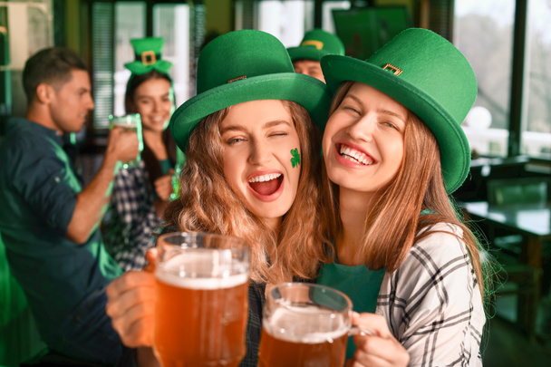 Young women with beer celebrating St. Patrick's Day in pub - Fotoğraf, Görsel