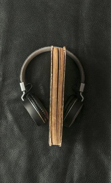 Close-up of old book with headphones covered on black leather ba - Photo, Image