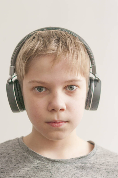 αγόρι με ακουστικά απολαμβάνει τη μουσική, κρατήστε τα χέρια σας στα ακουστικά - Φωτογραφία, εικόνα