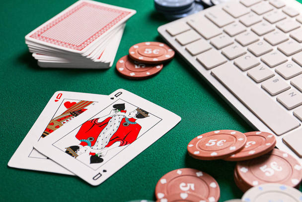 Chips and playing cards for gambling games with computer keyboard on color background - Photo, Image