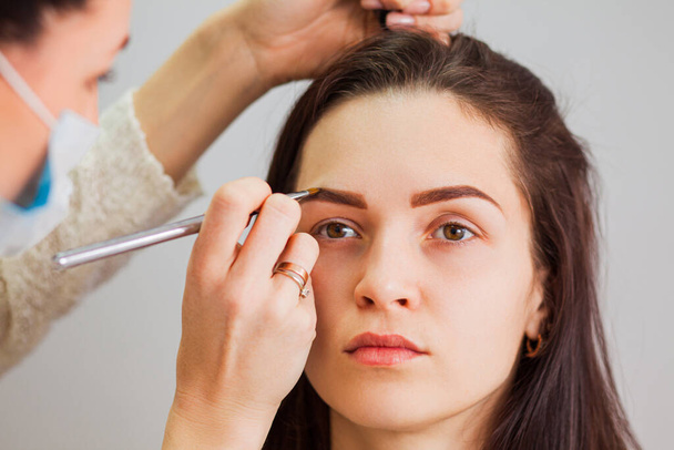Master makeup corrects and gives shape to eyebrows in a beauty salon - Foto, Imagen