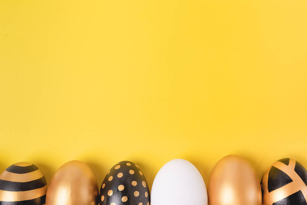 Flat Lay of Golden Easter Eggs em fundo amarelo. Conceito mínimo de Páscoa. Cartão de Páscoa feliz com espaço de cópia para texto. Vista superior. Horizontal
. - Foto, Imagem