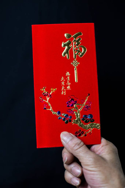 A person holding a Chinese traditional red envelop for the celebration of Chinese New Year, with Chinese scripts, meaning Congratulation and Good Luck - Valokuva, kuva