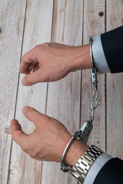Arrested businessman or official in handcuffs. Corruption or economic crime concept. - 写真・画像