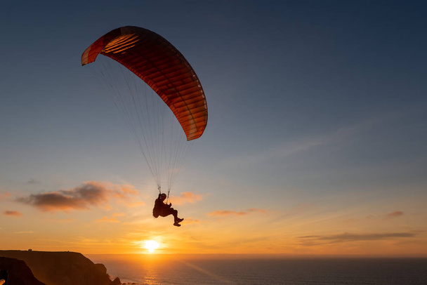 Gleitschirm fliegt bei Sonnenuntergang über das Meer. Gleitschirmsportkonzept. - Foto, Bild