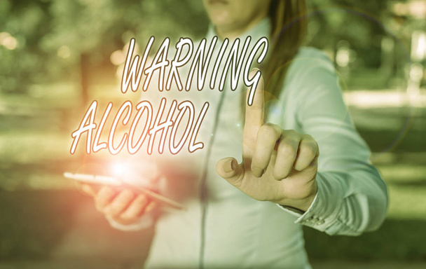 Znak tekstowy ostrzegający przed alkoholem. Biznesowe fotki wiadomości tekstowe pojawiają się na opakowaniach napojów alkoholowych Kobieta w niebieskich koszulkach biznesowych wskazując palcem na pustą przestrzeń - Zdjęcie, obraz