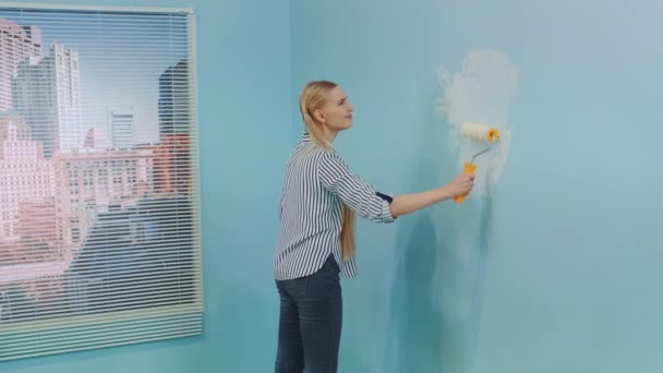 Μια γυναίκα διακοσμεί το γραφείο της βάφοντας τον τοίχο.. - Πλάνα, βίντεο