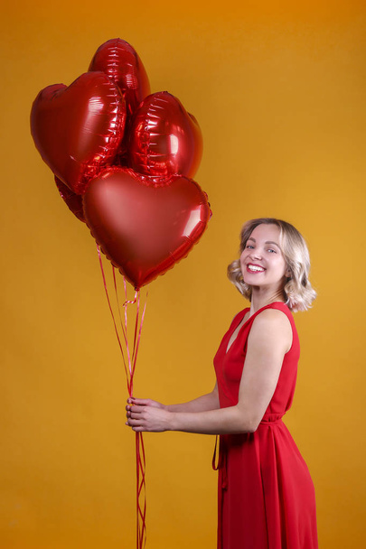 Cute female with shoulder length wavy hairstyle holding balloons. - 写真・画像