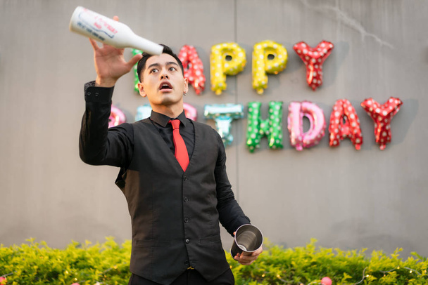 Asian bartender is warming up by practicing throwing bottles at  - Photo, Image