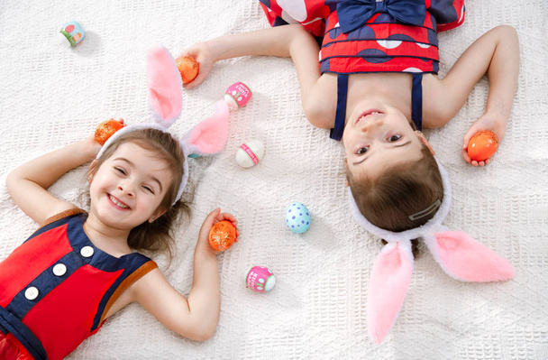Щасливого Великодня Дві смішні милі дівчата з великодніми яйцями і вухом кролика
 - Фото, зображення