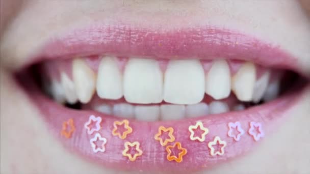 Makro widok uśmiechniętych żeńskich ust z dekoracyjnymi złotymi gwiazdami  - Materiał filmowy, wideo