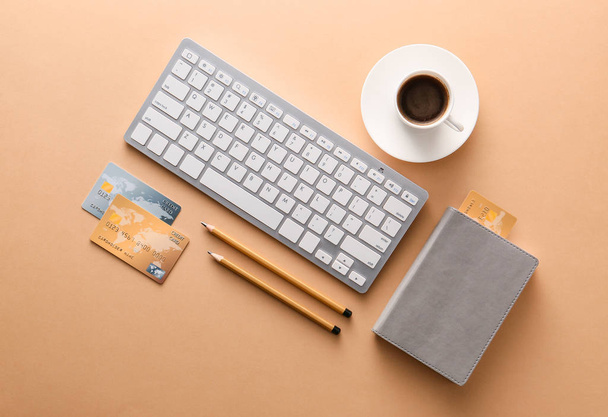 Кредитні картки з комп'ютерною клавіатурою, чашкою кави та канцелярських товарів на кольоровому фоні. Концепція онлайн банкінгу
 - Фото, зображення