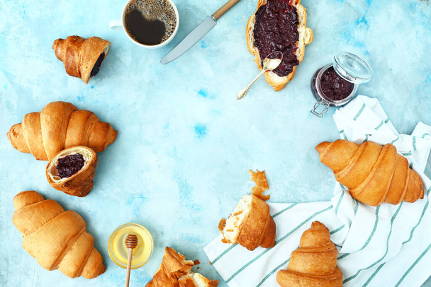 Tasty sweet croissants with jam, honey and coffee on color background - Photo, Image