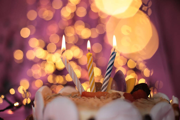 Vela ardiente en el pastel festivo brillante rosa fondo cumpleaños macro foto
 - Foto, imagen