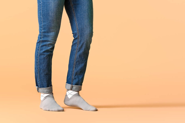 Male legs in socks and jeans on color background - Foto, Imagen