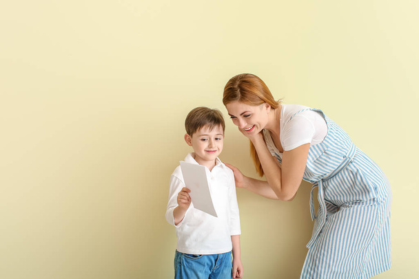 Happy little boy greeting his mother on color background - Фото, зображення