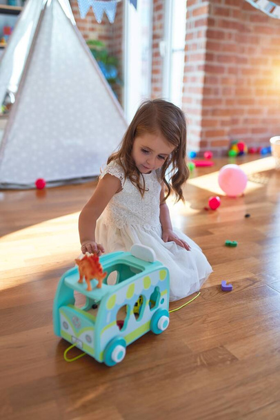 Adorável criança loira brincando com brinquedo de carro em torno de lotes de brinquedos no jardim de infância
 - Foto, Imagem
