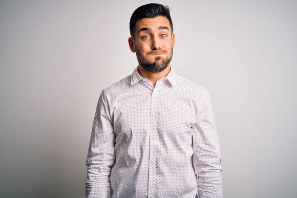 Young handsome man wearing elegant shirt standing over isolated white background puffing cheeks with funny face. Mouth inflated with air, crazy expression. - Photo, Image