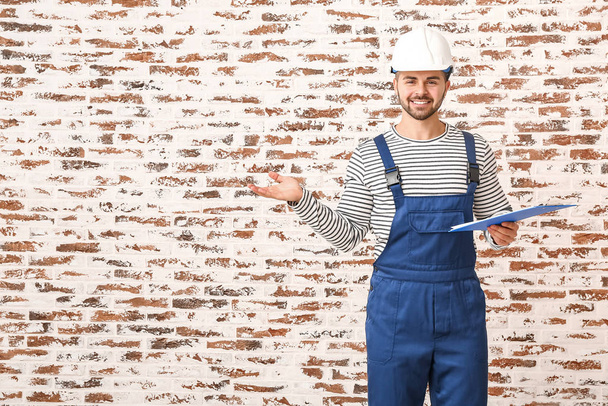 Bonito trabalhador masculino com prancheta no fundo de tijolo
 - Foto, Imagem