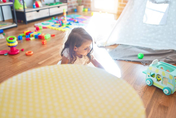entzückendes blondes Kleinkind spielt im Kindergarten um jede Menge Spielzeug - Foto, Bild