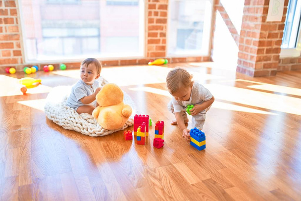Hermosos niños jugando alrededor de un montón de juguetes en el jardín de infantes
 - Foto, Imagen