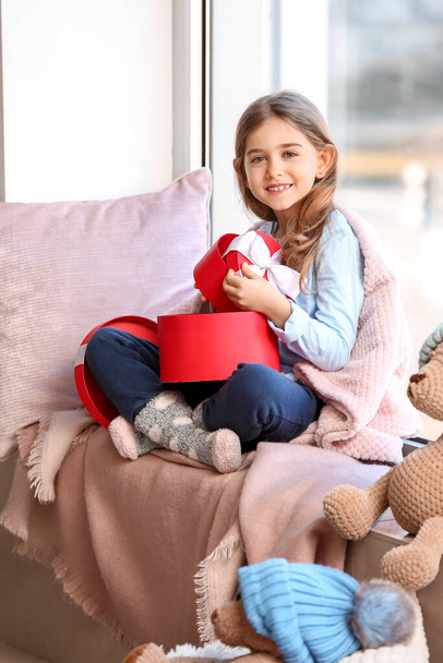 Cute little girl z prezentami na parapecie w domu - Zdjęcie, obraz