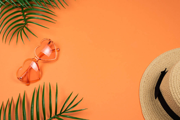 Gafas de sol rosadas y un sombrero sobre fondo naranja
.  - Foto, Imagen