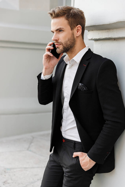 Charming young businessman wearing suit standing at the city - Photo, image