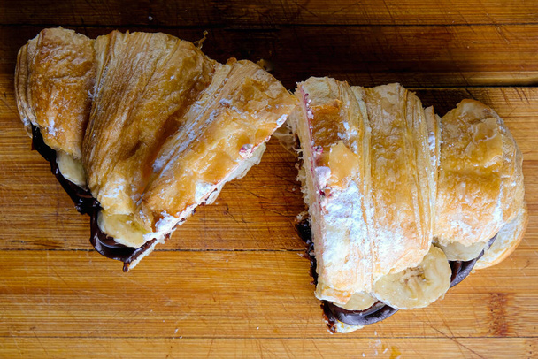 Croissant con burro al cioccolato e banana su fondo di legno
. - Foto, immagini