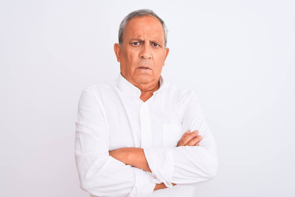 Senior grey-haired man wearing elegant shirt standing over isolated white background skeptic and nervous, disapproving expression on face with crossed arms. Negative person. - Photo, Image