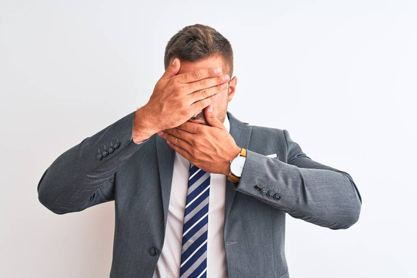 Young handsome business man wearing suit and tie over isolated background Covering eyes and mouth with hands, surprised and shocked. Hiding emotion - Fotografie, Obrázek
