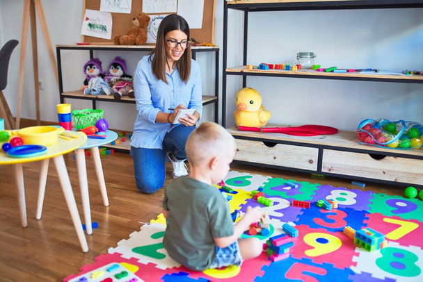 Mujer terapeuta joven que habla con el niño, consejero y corrección de comportamiento en la oficina alrededor de los juguetes
 - Foto, Imagen