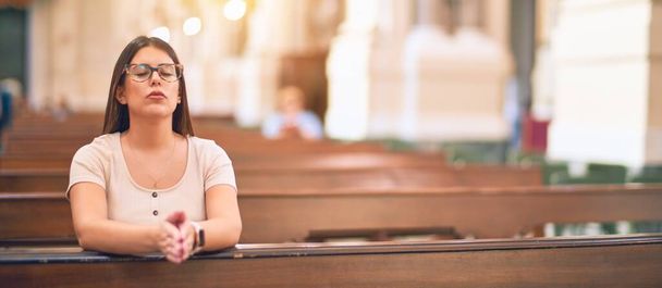 Joven hermosa mujer rezando de rodillas en un banco en la iglesia
 - Foto, imagen