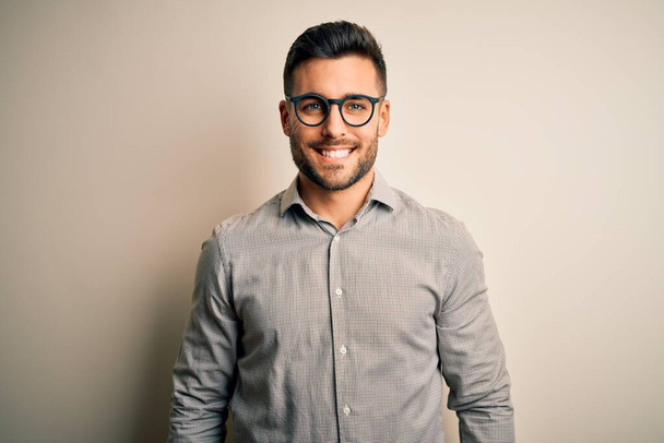 Young handsome man wearing elegant shirt and glasses over isolated white background with a happy and cool smile on face. Lucky person. - Φωτογραφία, εικόνα