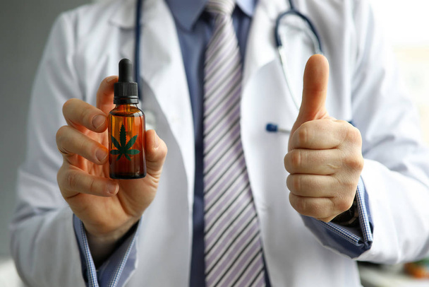 Male GP holding in hand cbd oil jar showing thumb up sign - Foto, imagen