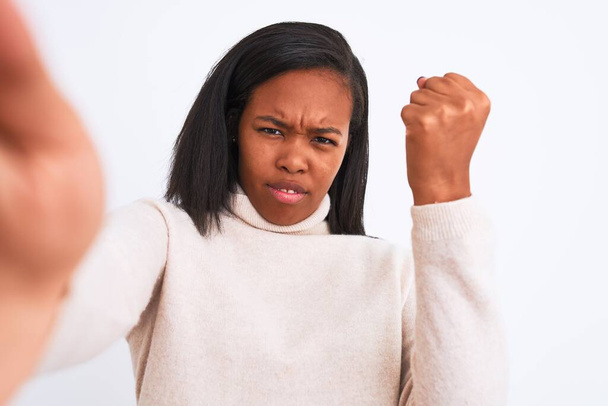 Beautiful young african american woman wearing turtleneck sweater taking a selfie annoyed and frustrated shouting with anger, crazy and yelling with raised hand, anger concept - Fotó, kép