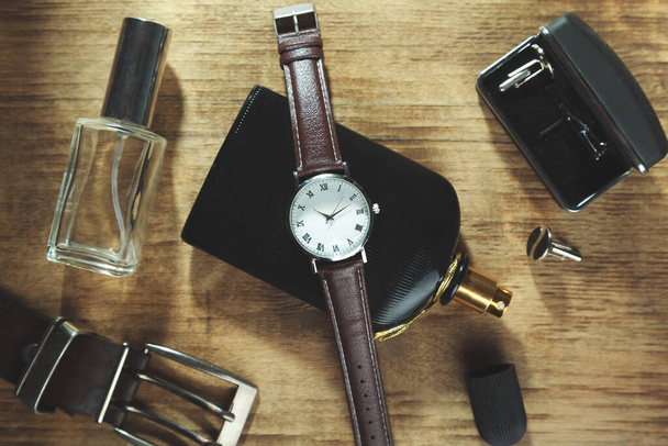 Men accessories: perfume, watch and belt on wooden background - Foto, Imagem