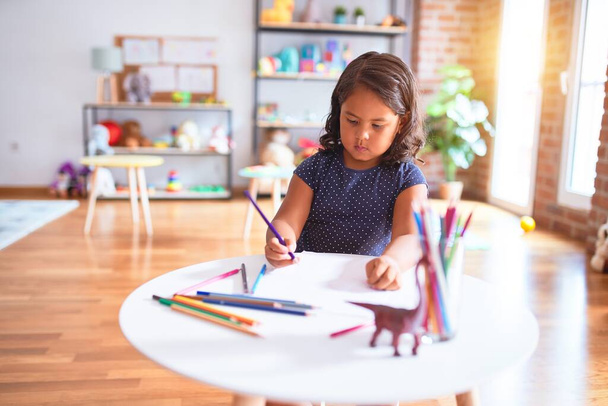 Mooie peuter meisje tekening leuke trekken met behulp van gekleurde potloden op de kleuterschool - Foto, afbeelding