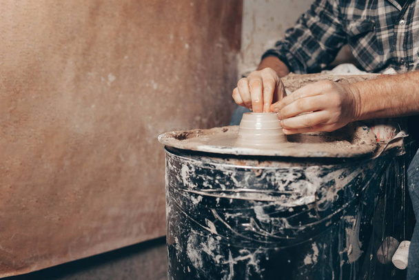 Homem forma um produto de argila branca em uma roda de cerâmica
 - Foto, Imagem